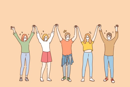 Friendship and having fun during COVID-19 pandemic concept. Group of young positive friends in protective medical face masks standing and holding raised hands in team during pandemic illustration