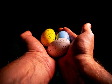 Easter chicken eggs in hand on a black background. Easter chicken eggs. Christ is risen. Christian religion. Religious holiday. Palms of human hands. Christian culture. Religious prayer. Tradition.