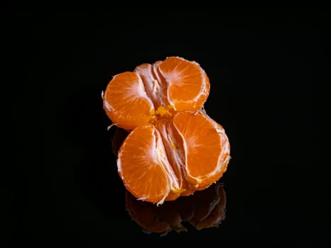 Peeled mandarin fruit slices on a black background. Orange tangerine. Orange Juice, Fruit Juice. Harvesting garden citrus fruits. Agriculture. Vegetarian food. Food photo. Background image.