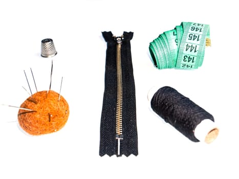 Knitted zipper and sewing accessories on a white background. Knitted zipper. Needles and threads. Sewing needles and threads. Tailor's centimeter. Sewing tool. Clothing sewing and repair.