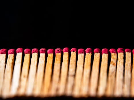Wooden matches with red sulfur heads on a black background. Fire ignition matches. Matchbox. Red sulfur. Black background. Wood material. Background image. Place for your text.