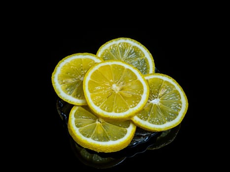Slices of citrus fruit yellow lemon on a black background. Citrus fruits of lemon. Yellow lemon fruit. Lemonade. Juice. Black background. Food photo. Garden harvest. Natural vitamins.