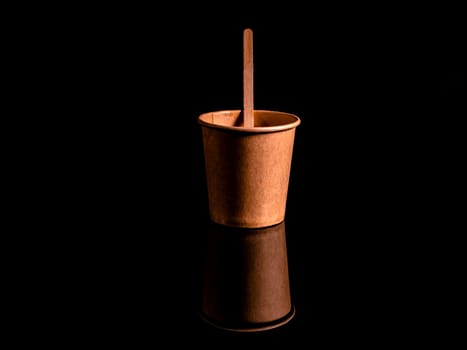 Disposable cardboard coffee cups on a black background. Cardboard colored cups. Disposable tableware. Coffee drinks. Paper dishes for drinks. Hot tea. Black background. Darkness.