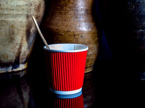 Disposable cardboard cups for coffee on a black background. Cardboard glass. Disposable tableware. Coffee drinks. Red color. Paper dishes for drinks. Black background. Darkness.