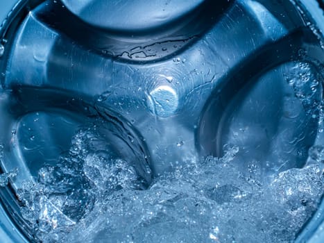 Rotating drum in the washing machine tub with water. Washer. Automatic laundry. Service and repair of equipment. Splashing water. Repair shop. Stainless steel tank. Centrafuga.