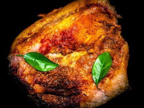 A piece of baked pork with green laurel leaves. Meat dish. Baked ruddy pork skin. Fried lard. Lard cooked on fire. Seasoning with bay leaves. Cooking food. Home kitchen. Kitchen menu.