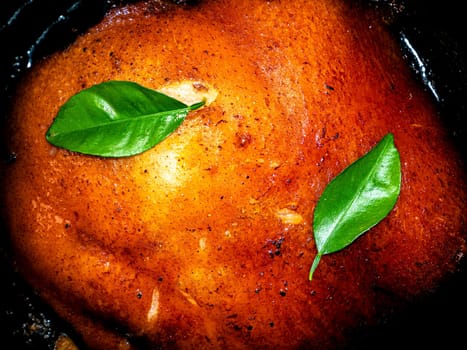 A piece of baked pork with green laurel leaves. Meat dish. Baked ruddy pork skin. Fried lard. Lard cooked on fire. Seasoning with bay leaves. Cooking food. Home kitchen. Kitchen menu.