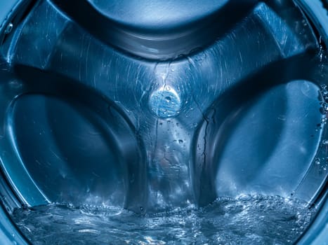 Rotating drum in the washing machine tub with water. Washer. Automatic laundry. Service and repair of equipment. Splashing water. Repair shop. Stainless steel tank. Centrafuga.