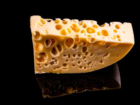 A piece of hard cheese on a black background. Hard cheeses. Milk product. Dairy products. Home kitchen. Food photo. Black background. Yellow. Healthy eating. Background image.