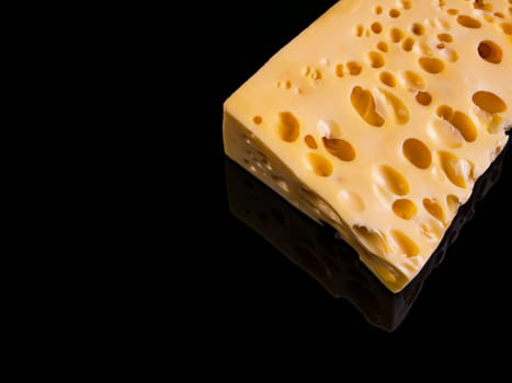 A piece of hard cheese on a black background. Hard cheeses. Milk product. Dairy products. Home kitchen. Food photo. Black background. Yellow. Healthy eating. Background image.