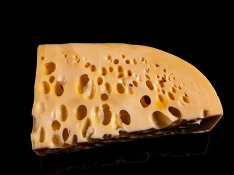 A piece of hard cheese on a black background. Hard cheeses. Milk product. Dairy products. Home kitchen. Food photo. Black background. Yellow. Healthy eating. Background image.