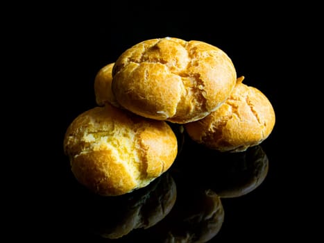 Baking choux pastry on a black background. Flour dessert. Custard cake. Sweet dessert. Sweet food. Pastry. Baking with cream. White bread. Black background. Wheat flour bun. Menu of dishes.