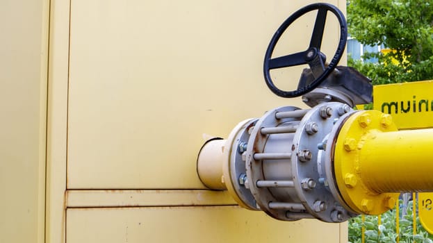 Yellow gas pipe with a tap. Oil pipeline fittings in the oil and gas industry. Oil and gas processing plant with pipeline fittings. Industrial safety valve