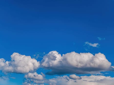 White cloud against blue sky in sunlight. White cumulus clouds. Blue sky. Sunlight. Cloudy horizon. Natural background. Atmosphere and stratosphere. Weather forecast. Space. Air flight.