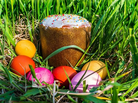 Colored chicken Easter eggs in green grass. Easter holiday. Bread. Egg. Green grass. Christian religion. Religious holiday. Spring season. Christian faith. Sunday event. Resurrection of God.