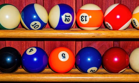 Colored billiard balls on a wooden shelf. Billiard ball. Wooden shelf. Numbered balls. Gambling. Sports game. Leisure activities. Business. Background image.