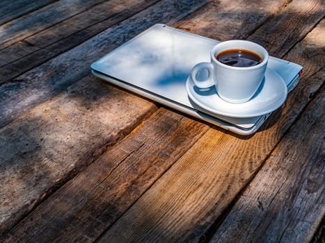 Laptop and a cup of coffee on a wooden table. Coffee drink. Cup and saucer. Portable computer. Wooden table. Distant work. Earning money on the Internet. Internet cafe. Computer business.