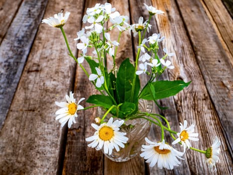 Bouquet of white daisies flowers in a glass vase on a wooden table. White daisies. Bouquet of flowers. Deyoyanny background. Flowering period. Congratulate with celebration. Gift for a woman.