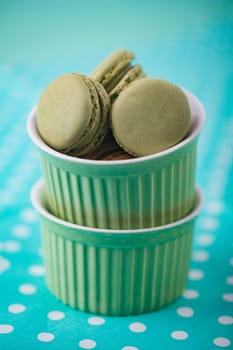 Sweet Macarons with green bowls and green fabric background