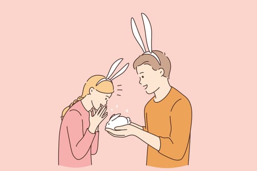 Funny cute present for girl concept. Young smiling boy cartoon character wearing rabbit ears giving white small rabbit gift for his surprised happy girlfriend vector illustration
