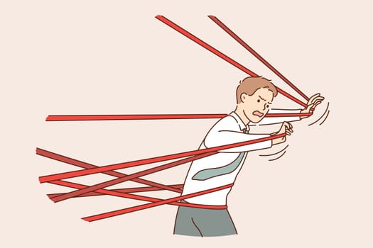 Business difficulty, problem, struggling concept. Angry businessman tied up with red tape trying to run away with full effort and feeing anger rage trying to overcome to reach success