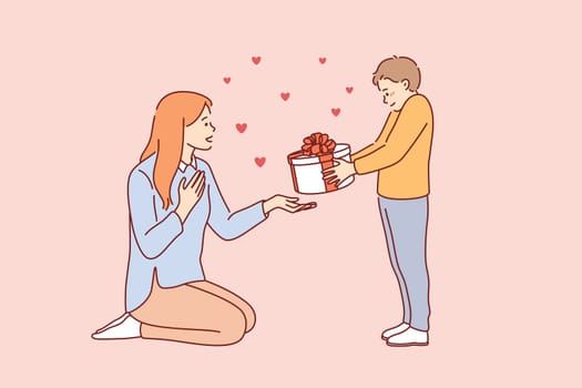 Celebrating Happy Mothers day concept. Small smiling boy cartoon character standing giving present box to his young mother for holiday vector illustration