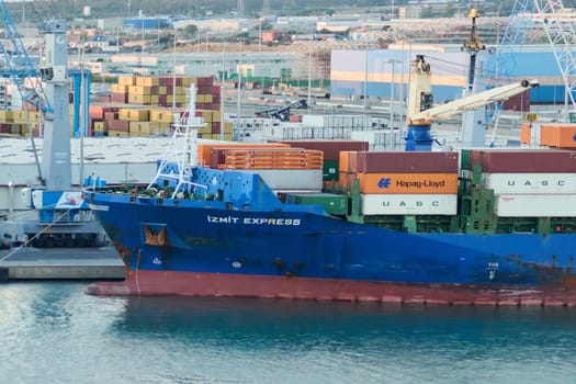 Civitavecchia, Italy - February 17, 2025: Cargo ship IZMIT EXPRESS docked in the port of Civitavecchia, Italy, with containers stacked on the deck. Busy port scene with cranes and stacked containers.