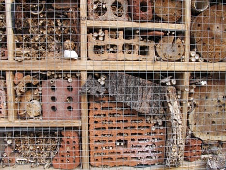 Insect hotel with brick, bamboo sticks, bark and log