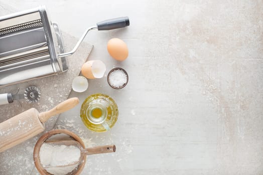 Making homemade fresh ravioli pasta with machine on kitchen table with some ingredients around