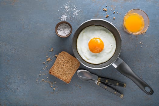 Continental Breakfast meal of fried egg in pan served with bread and juice top view. Healthy breakfast tabel