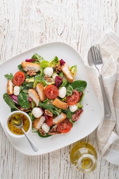 Healthy salad with crispy fried chicken breast strips, cheese and tomatoes