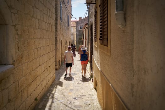 Tourists in a narrow alley in the old town of Krk on the island of the same name in Croatia on a hot summer day