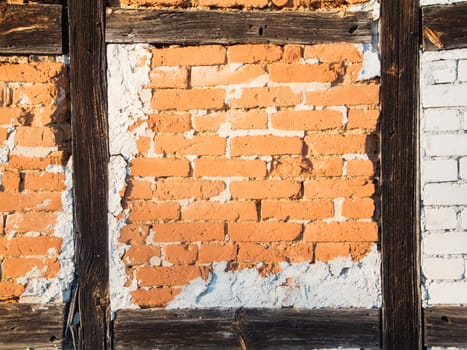 Detail view of a half-timbered wall with exposed bricks  Sandstones and cement stains in the light of the evening sun.