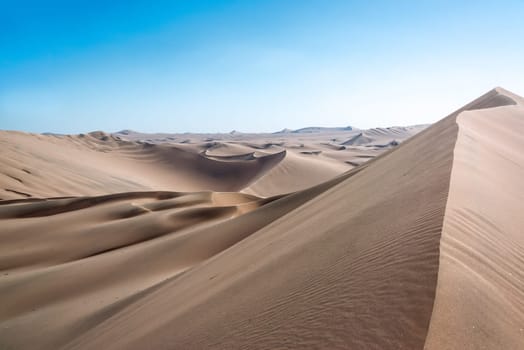 Sand dune landscape seen from the top of a dune at Huacachina, Peru