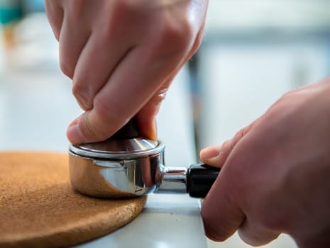 hands with porta filter and espresso tamper