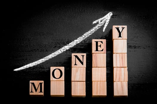 Ascending arrow above bar graph of Wooden small cubes isolated on black background. Chalk drawing on blackboard. Business Concept image.EE