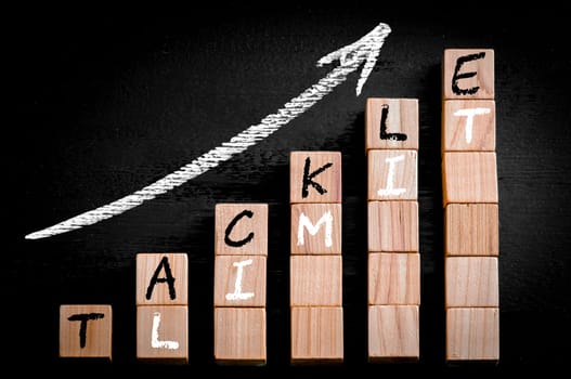 Message TACKLE LIMIT on ascending arrow above bar graph of Wooden small cubes isolated on black background. Chalk drawing on blackboard. Business Concept image.