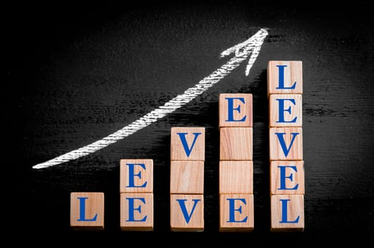 Ascending arrow above bar graph of Wooden small cubes isolated on black background. Chalk drawing on blackboard. Business Concept image.