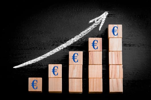 Ascending arrow above bar graph of Wooden small cubes isolated on black background. Chalk drawing on blackboard. Business Concept image.
