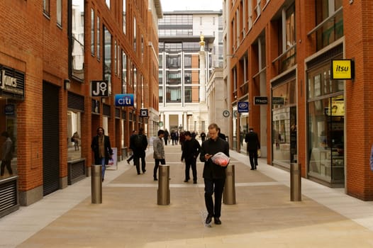 London,United Kingdom - March 31,2015: Businessmen and passers-by walk along a shopping street in front of the monument on March 31,2015 in London.