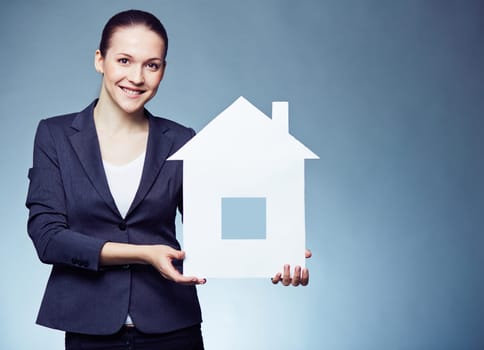 Cheerful female realtor showing paper house