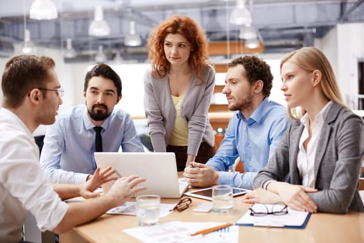Group of business partners listening to colleague at meeting