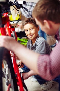 Cute boy learning to repair bike in garage