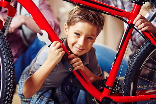 Little boy with wrench looking at camera in garage