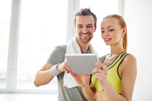 Young sporty couple using touchpad in gym