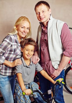 Happy couple and little boy on bicycle looking at camera