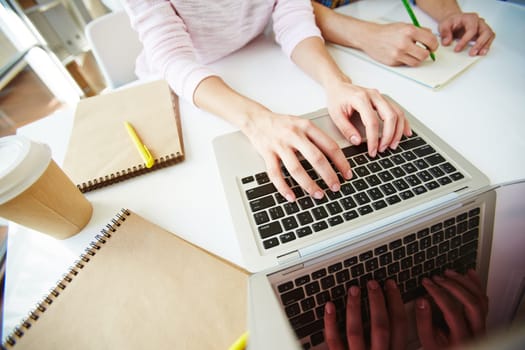 Female student typing on laptop at workplace