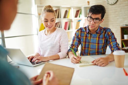Group of teenage friends doing home task in library