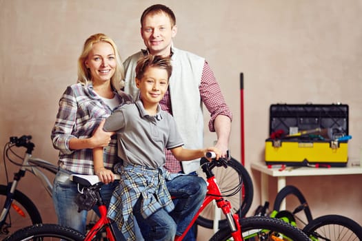 Happy young couple and their son looking at camera in garage