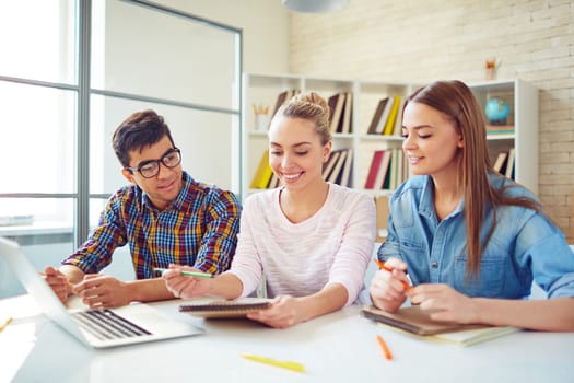 Group of happy teenage friends looking through notes